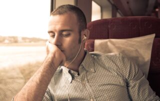 Mann sitzt nachdenklich im Zug und hört Musik