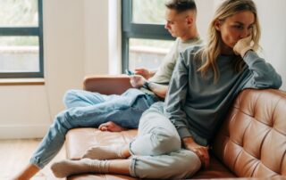 Frau und Mann sitzen voneinander abgewandt auf einem Sofa